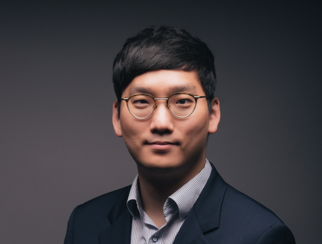 안경을 쓰고 짙은 색 정장을 입은 이홍석 뉴로클 대표가 카메라를 응시하며 인터뷰 촬영에 임하고 있다.
