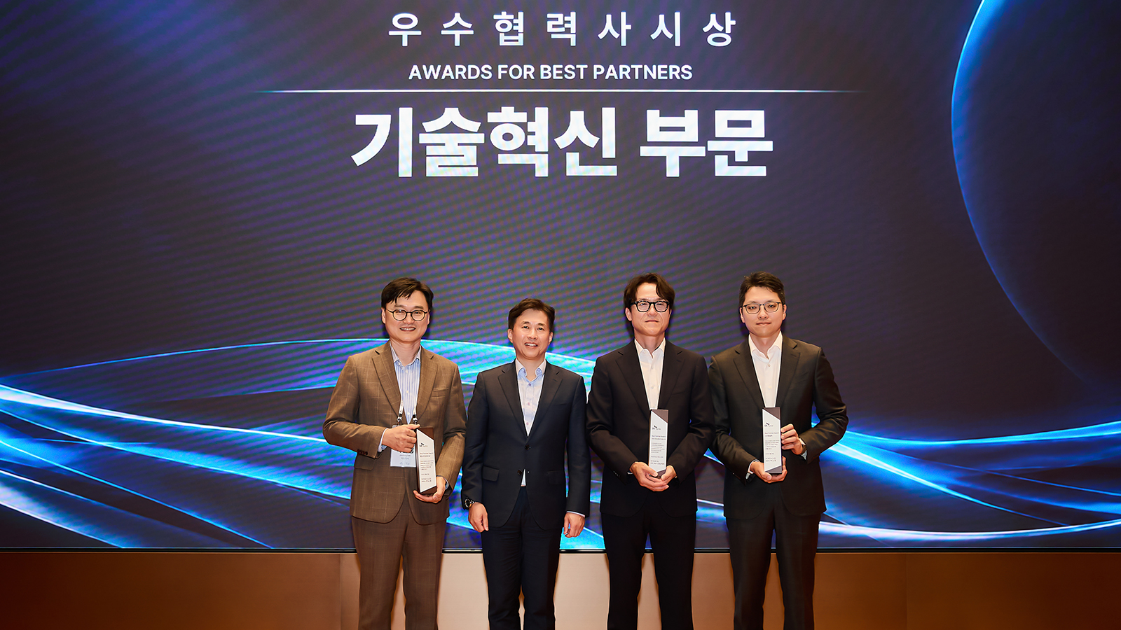 우수협력사 시상식에서 기술혁신 부문 트로피를 든 수상자 4명이 SK하이닉스 관계자와 함께 기념 촬영을 하고 있다.