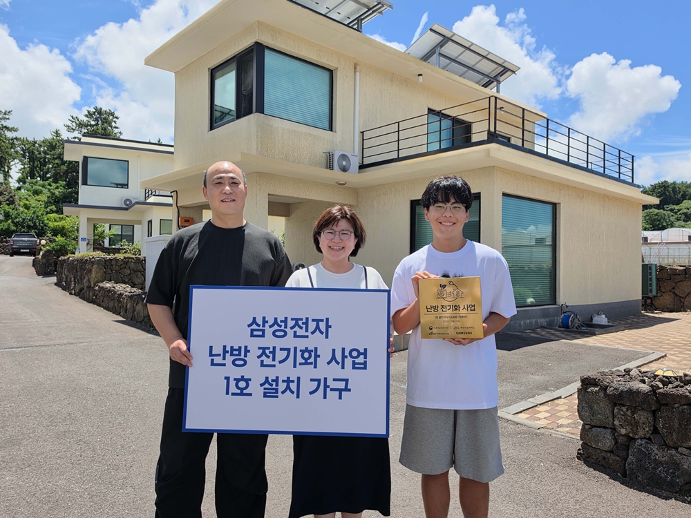 태양광 패널이 설치된 주택 앞에서 가족이 삼성전자 난방 전기화 사업 1호 설치 가구 팻말과 인증패를 들고 있다.