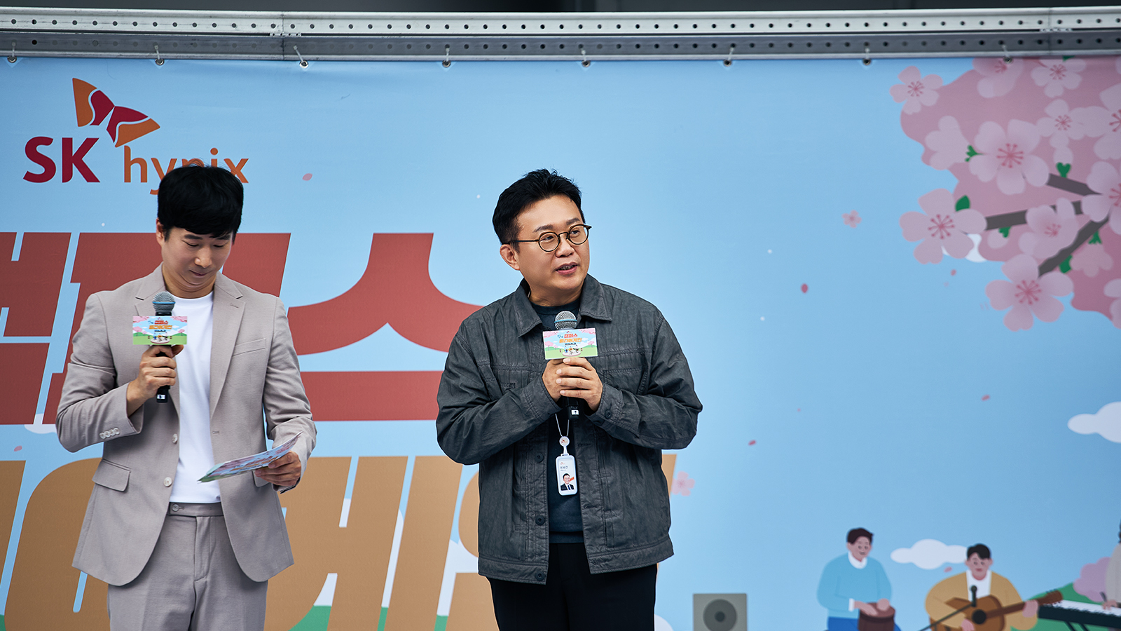 SK하이닉스 봄맞이 사내 행사 무대에서 사회자와 관계자가 마이크를 들고 인사말을 전하고 있다.