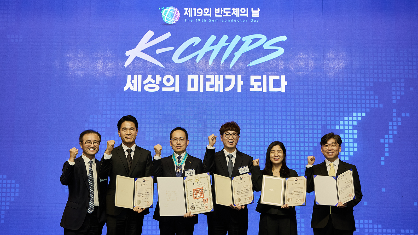 제19회 반도체의 날 기념식에서 수상자들이 표창장을 들고 주먹을 쥐며 기념촬영을 하고 있다.