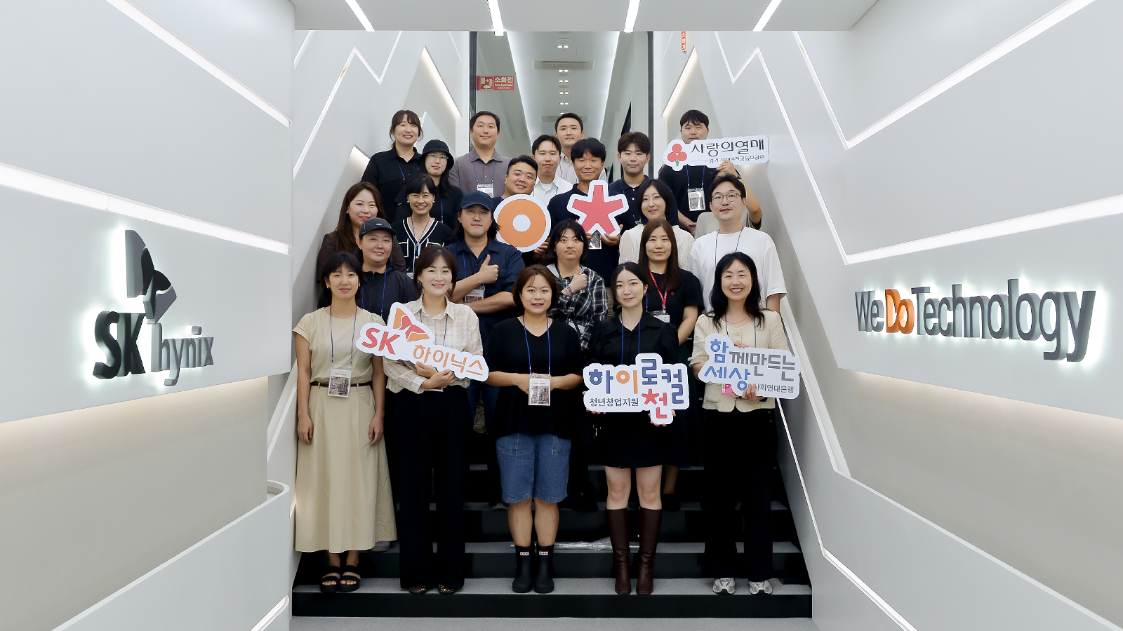 SK하이닉스 본사 계단에서 관계자들이 '하이로컬이천' 등 피켓을 들고 단체로 기념 촬영을 하고 있다.