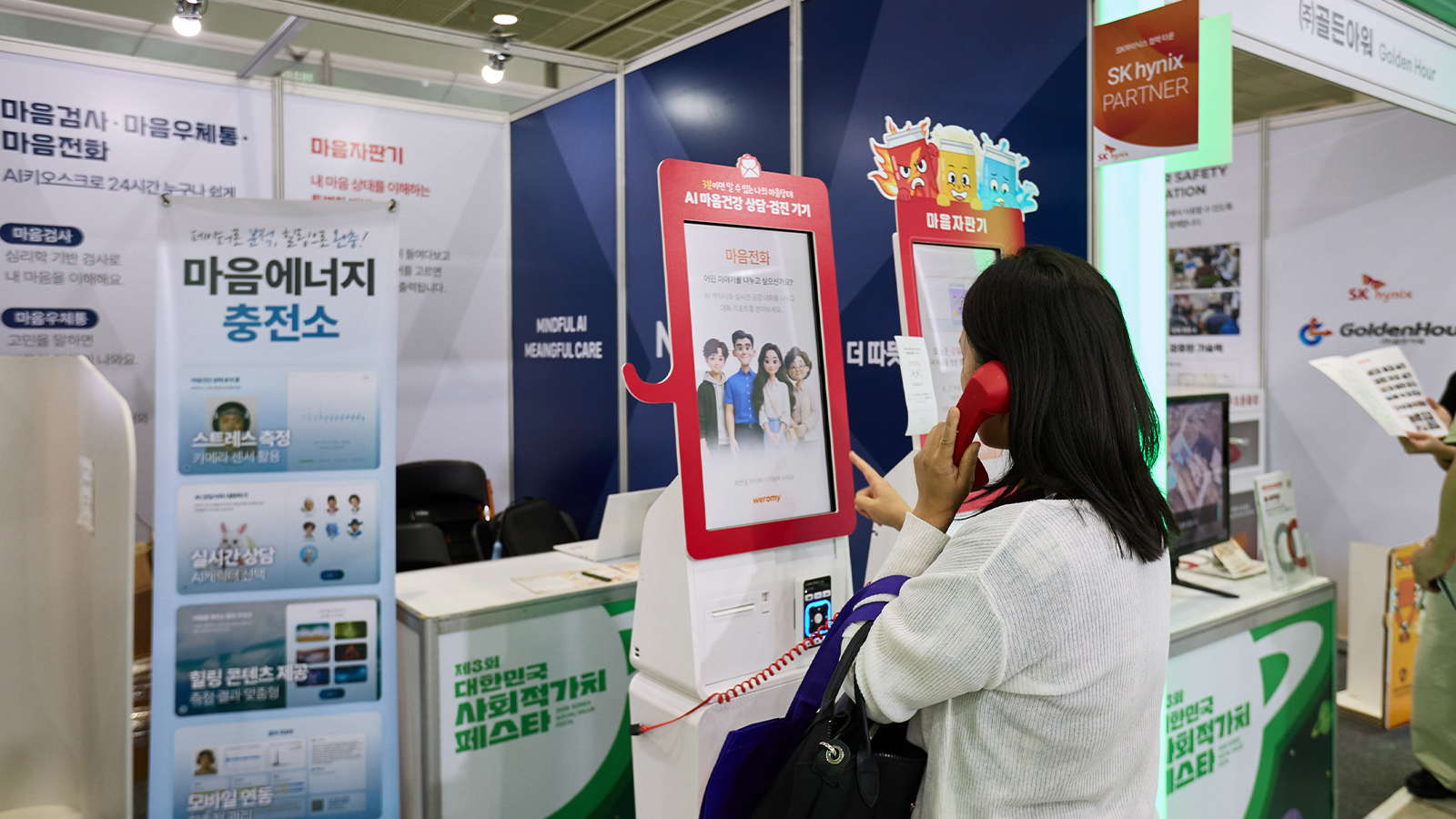 관람객이 사회적가치 페스타 부스에서 AI 마음건강 상담 키오스크 '마음전화' 수화기를 들고 체험하고 있다.