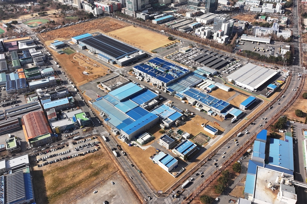 파란색 지붕의 공장 건물들이 밀집한 산업단지 항공 전경, HVAC 생산라인 부지로 예정된 지역.