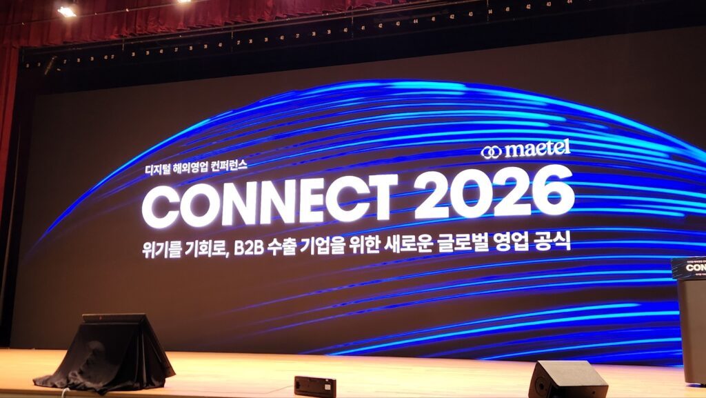 메텔이 개최한 '커넥트 2026' 디지털 해외영업 컨퍼런스 무대 스크린에 B2B 수출 기업을 위한 새로운 글로벌 영업 공식이라는 문구가 표시되어 있다.