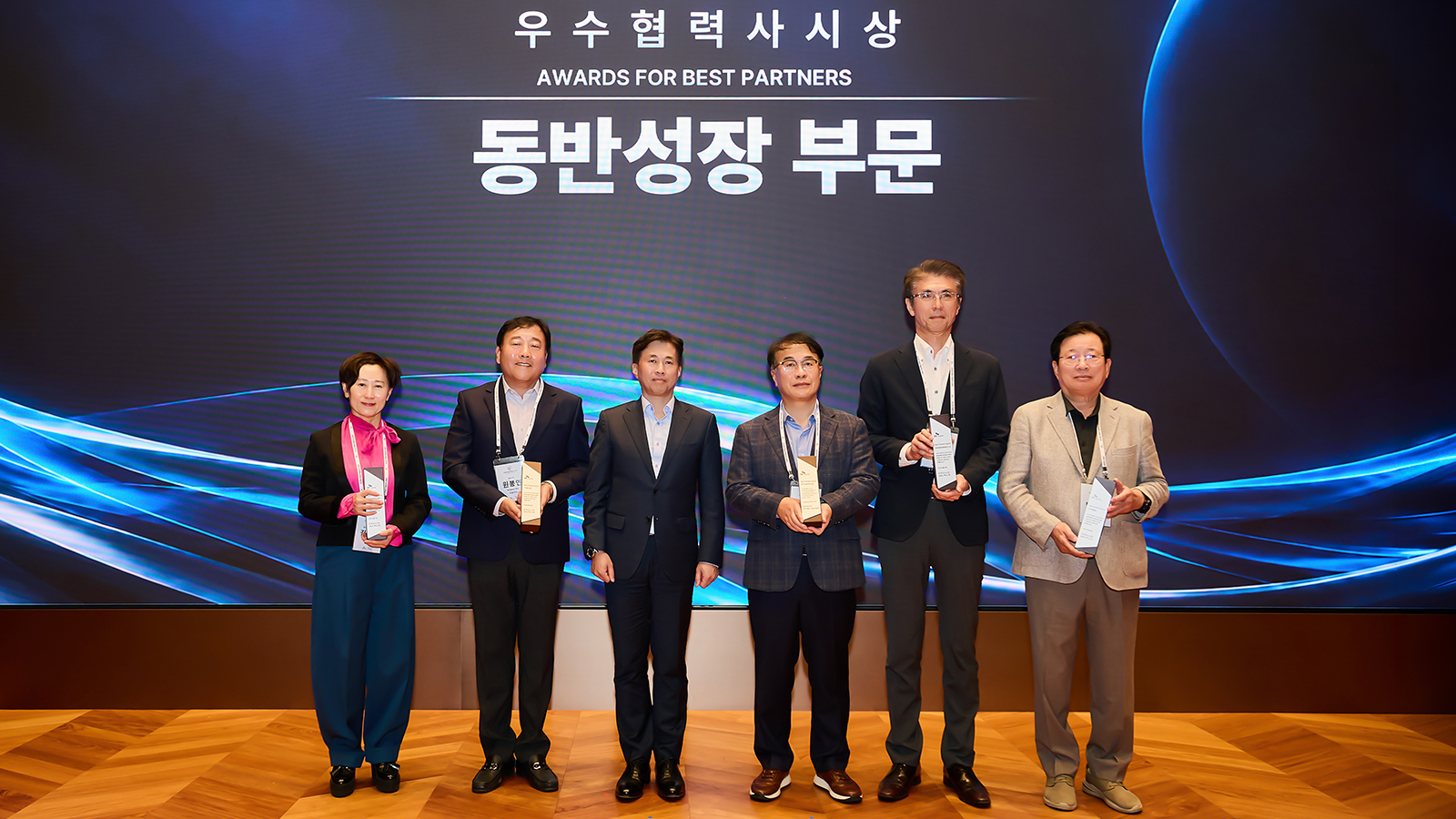 우수협력사시상 동반성장 부문 수상자들이 트로피를 들고 무대 위에서 기념 촬영을 하고 있다.