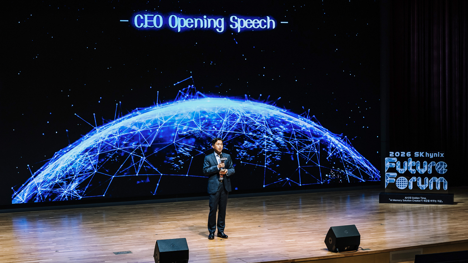 SK하이닉스 CEO가 '2026 SK하이닉스 퓨처포럼' 무대에서 개회사를 하고 있는 모습, 뒤로 지구 네트워크 이미지가 보인다.