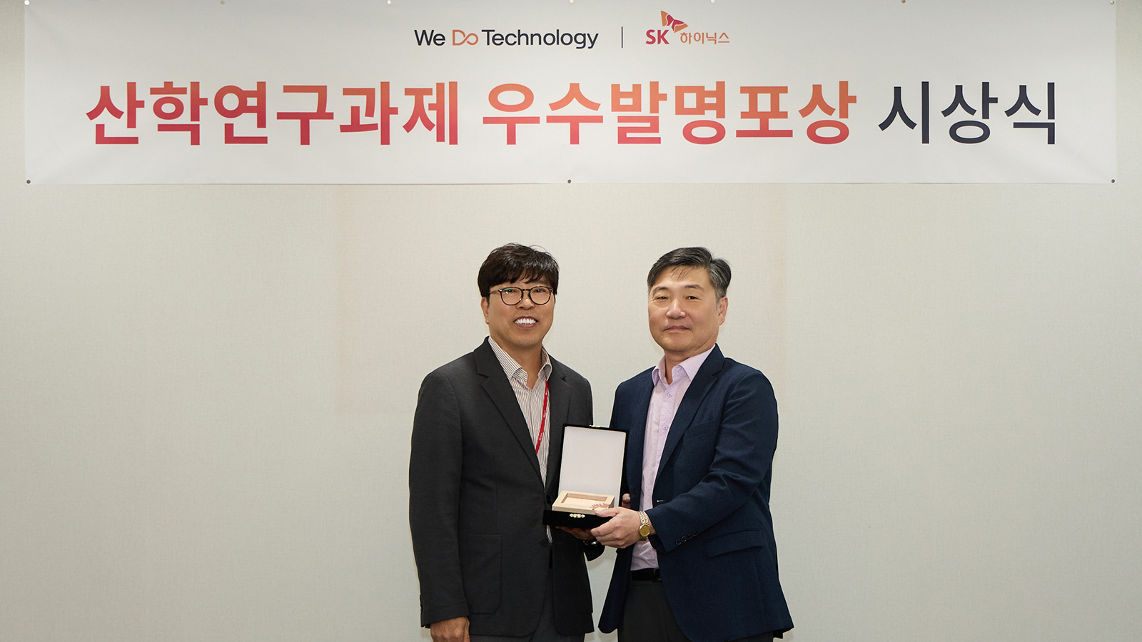 SK하이닉스 산학연구과제 우수발명포상 시상식에서 관계자 두 명이 상패를 들고 기념 촬영을 하고 있다.