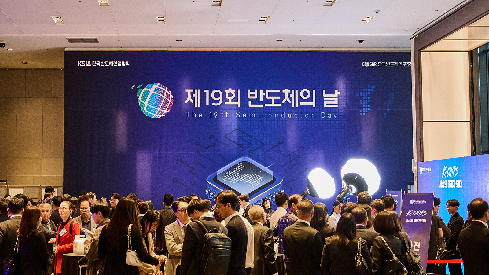 제19회 반도체의 날 행사장에서 참석자들이 모여 있는 모습, 뒤편에 행사 홍보 현수막이 보인다.