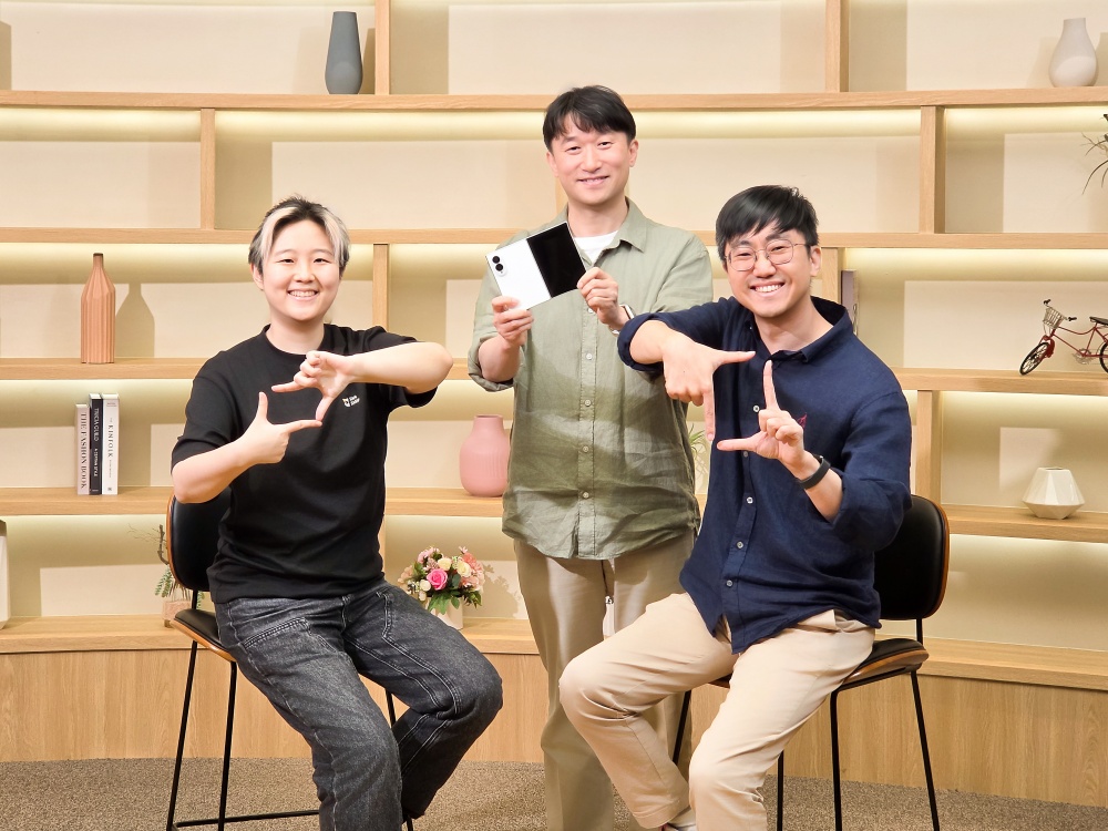 갤럭시 Z 폴드8을 든 남성과 카메라 프레임 포즈를 취한 두 명의 개발자가 인터뷰를 위해 포즈를 취하고 있다.