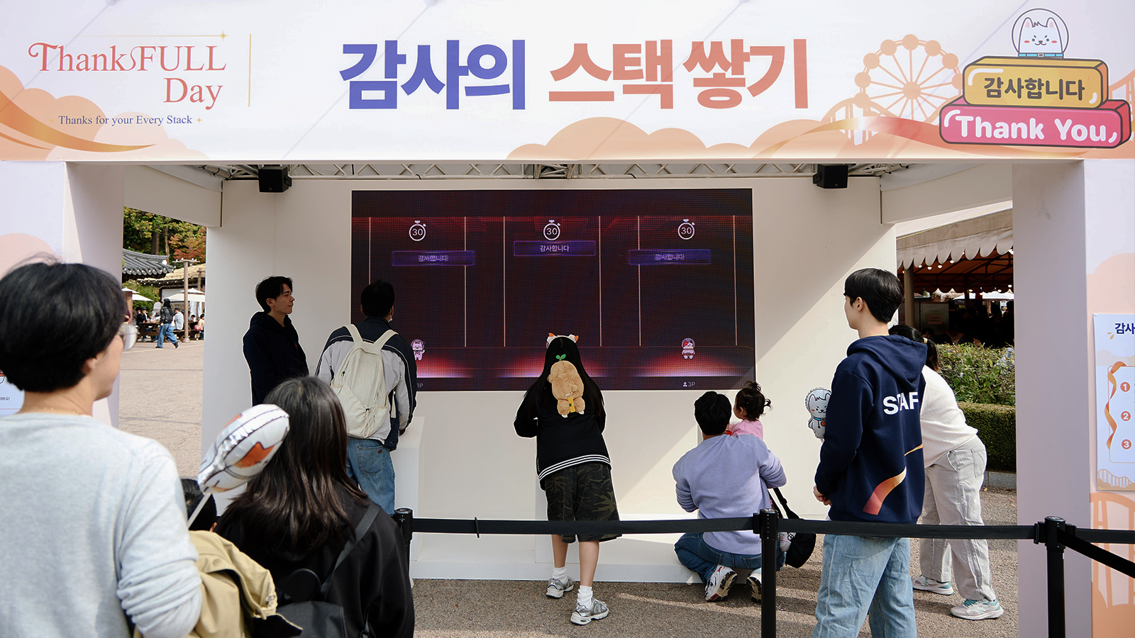 'ThanksFULL Day' 행사장에서 관람객들이 '감사의 스택 쌓기' 체험 부스 화면 앞에 줄지어 서 있다.