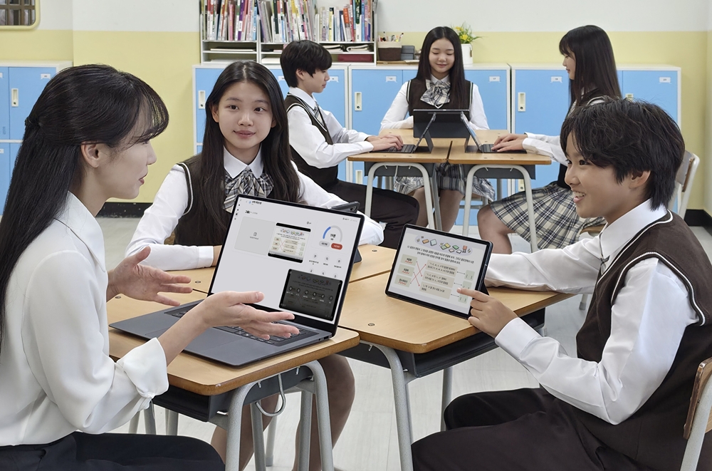 교실에서 학생들이 태블릿과 노트북으로 삼성 녹스 클래스룸 화면을 보며 교사와 수업하는 모습