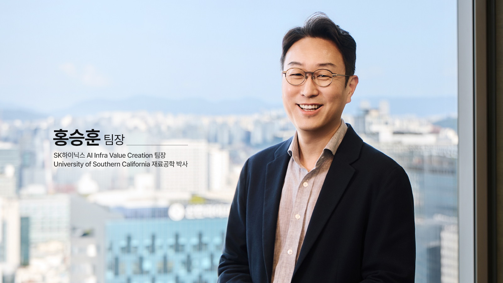 SK하이닉스 홍승훈 AI Infra Value Creation 팀장이 도심 전경을 배경으로 미소 지으며 서 있는 모습.