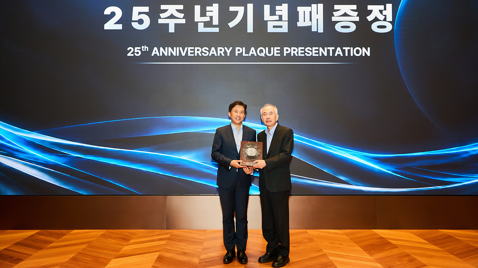 SK하이닉스 관계자와 협력사 대표가 무대에서 25주년 기념패를 함께 들고 기념 촬영을 하고 있다.