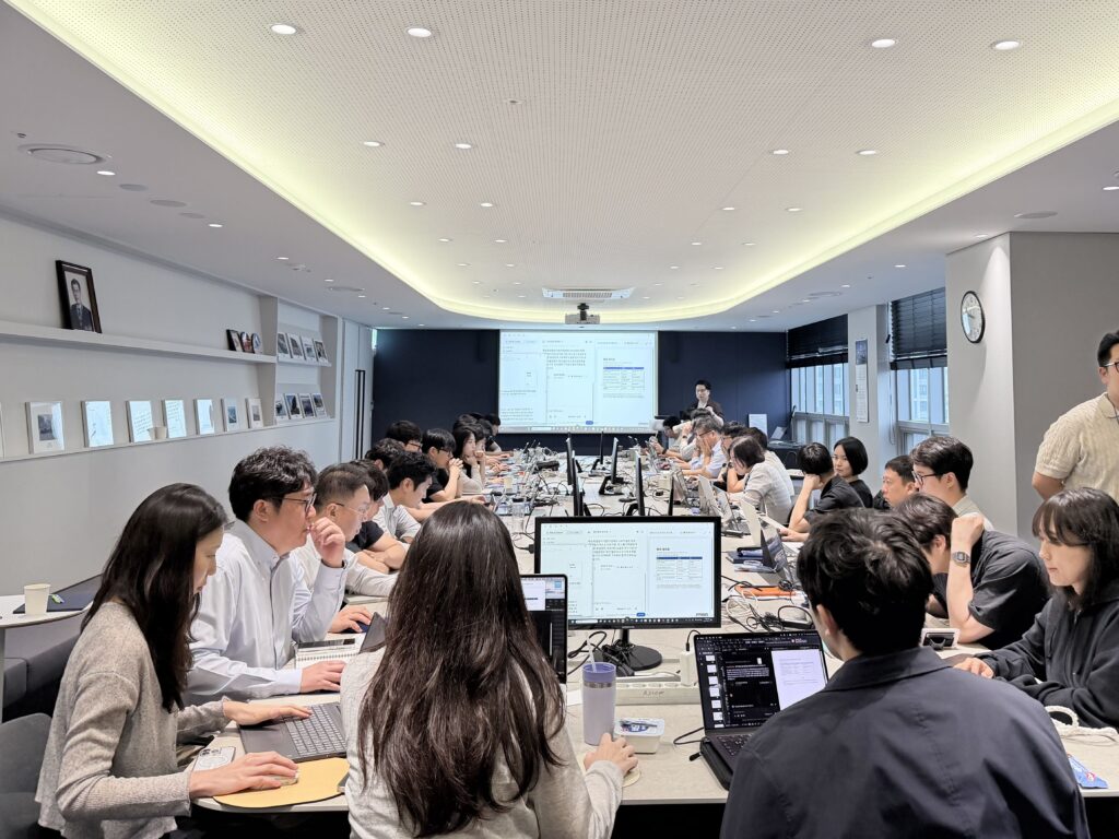 직원들이 회의실에 모여 노트북과 모니터로 AI 활용 교육을 진행하는 모습.