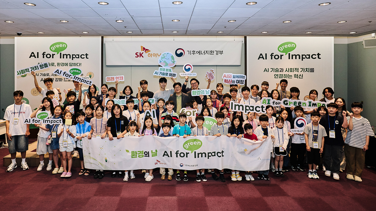 SK하이닉스와 기후에너지환경부가 개최한 'AI for Green Impact' 행사에서 어린이 참가자들과 관계자들이 '환경의 날' 현수막을 들고 단체 기념촬영을 하고 있다.